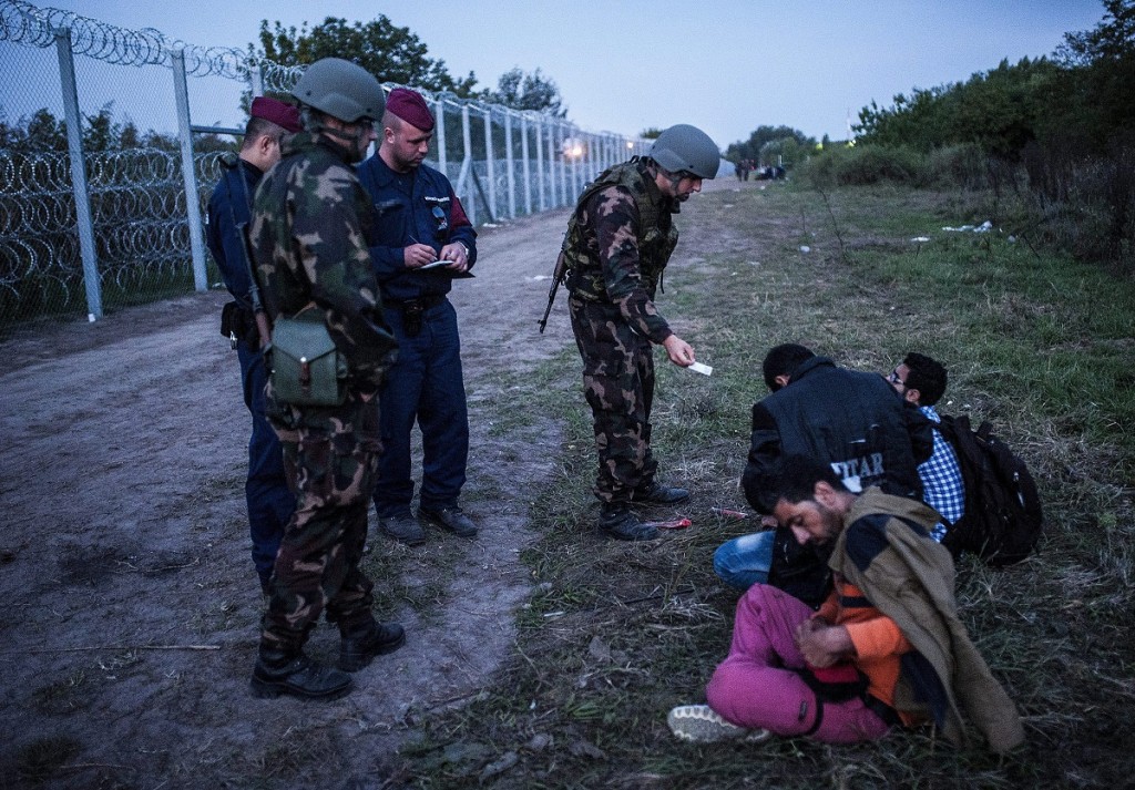 Röszke, 2015. szeptember 15. Katonák és rendõrök három elfogott illegális bevándorlót õriznek a biztonsági határzár mellett a szerb-magyar határon, Röszke térségében 2015. szeptember 15-én. Szeptember 15-én hatályba léptek a migrációs helyzet miatti új szabályozások. MTI Fotó: Ujvári Sándor